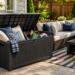 Modern weather-resistant resin deck box on a stylish backyard patio storing outdoor cushions, gardening tools, and patio accessories.