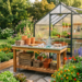 Wooden potting bench beside a backyard greenhouse and raised garden beds filled with vegetables, herbs, and colorful flowers.